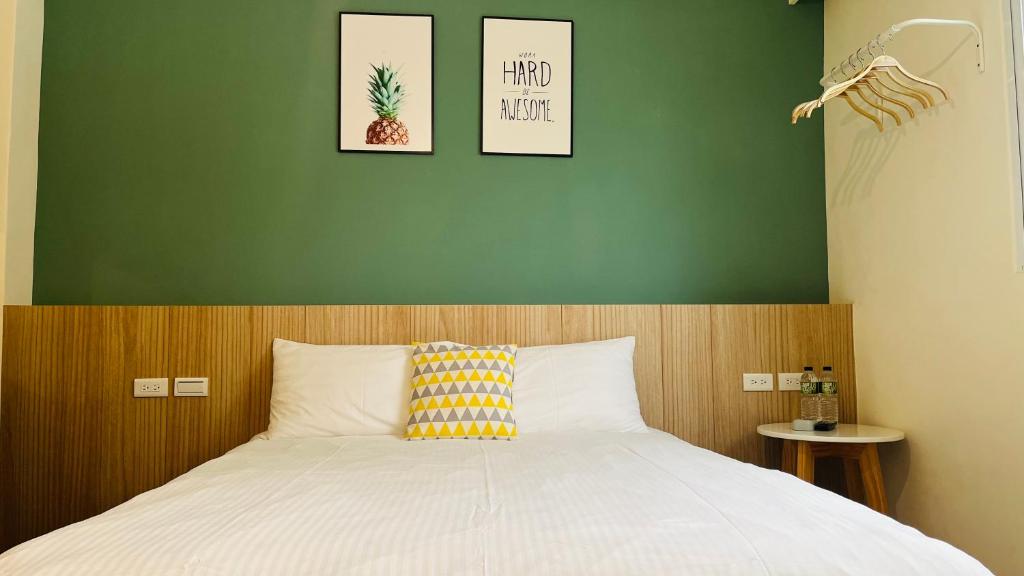 1 dormitorio con 1 cama con pared verde en 古栗Chestnut Guest House-可包棟民宿, en Taitung