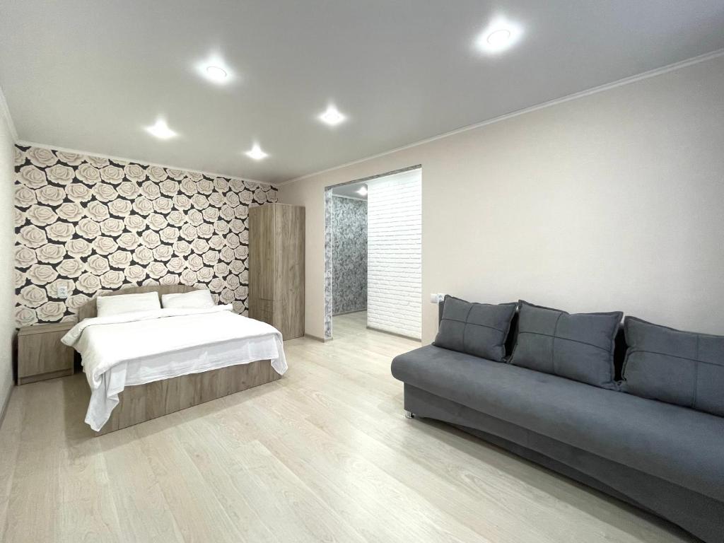 un dormitorio con una cama y un sofá en Квартира DOSTYK MALL, Университет, en Petropavlovsk