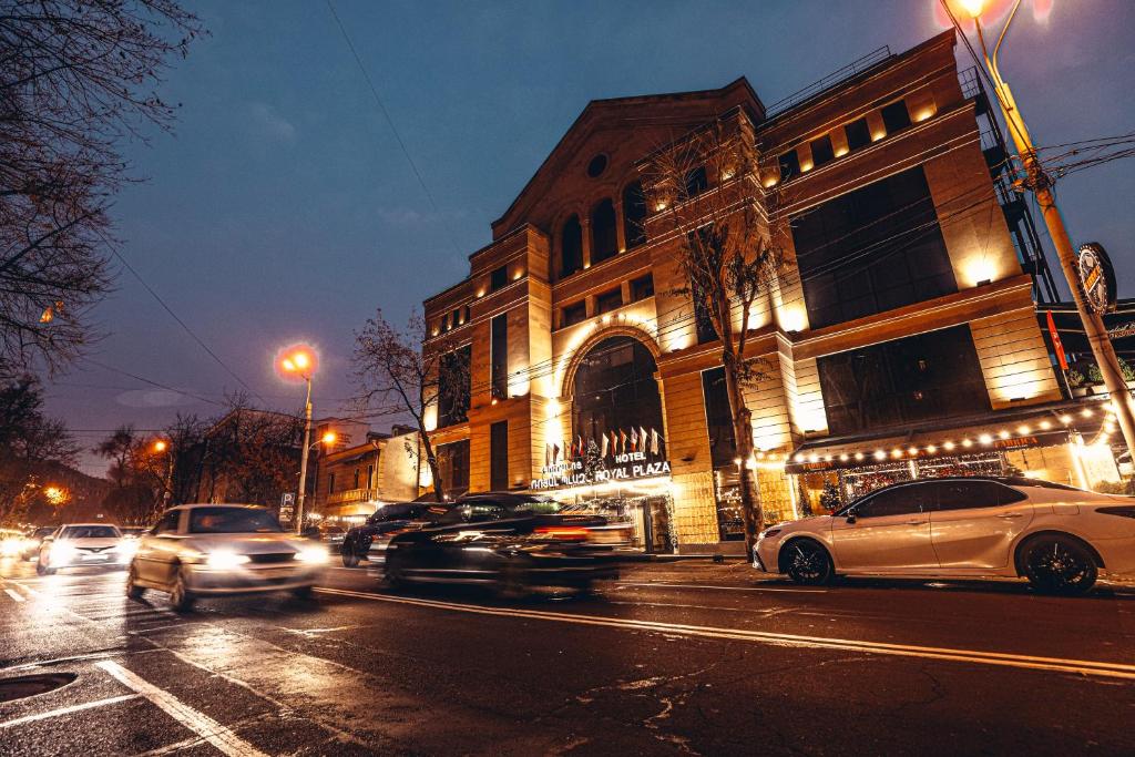 un grupo de coches conduciendo por una calle de la ciudad por la noche en Royal Plaza by Stellar Hotels, Yerevan, en Ereván