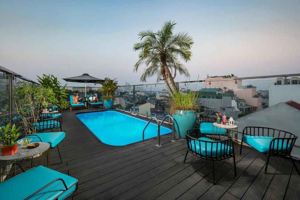 um deque no último piso com uma piscina, mesas e cadeiras em San Palace Hotel & Spa em Hanói