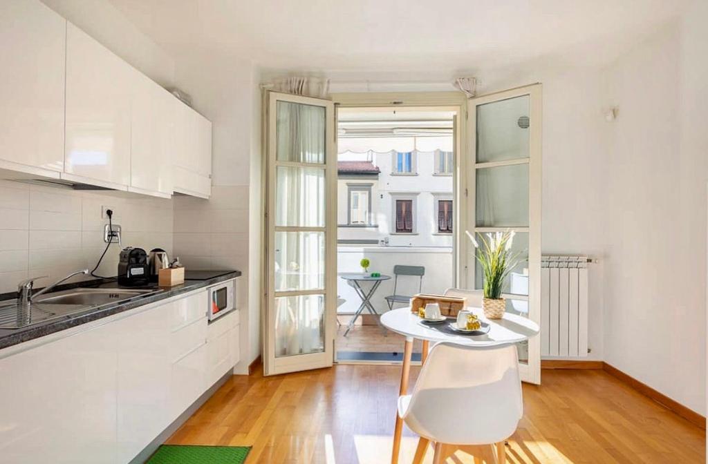 une cuisine avec des placards blancs et une table dans l'établissement Florence Green Apartment, à Florence