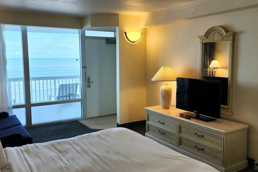 - une chambre avec un lit, une télévision et un balcon dans l'établissement Sandy Toes Beachfront Condo, à Daytona Beach