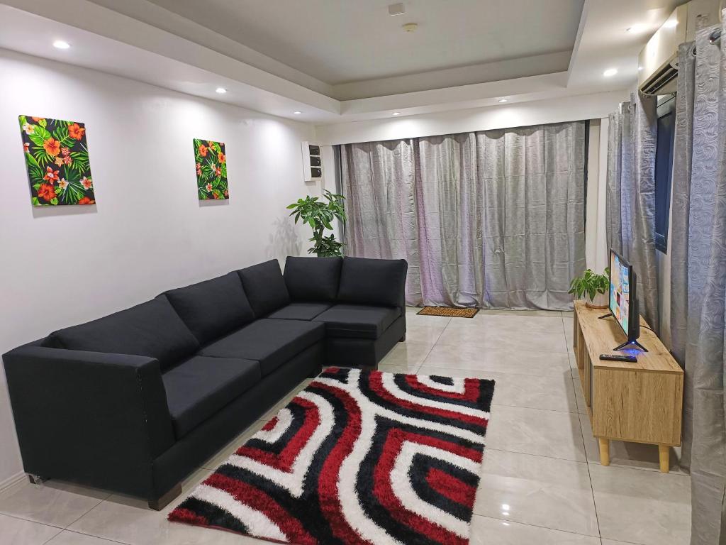 sala de estar con sofá negro y alfombra en Pacific Apartment en Suva