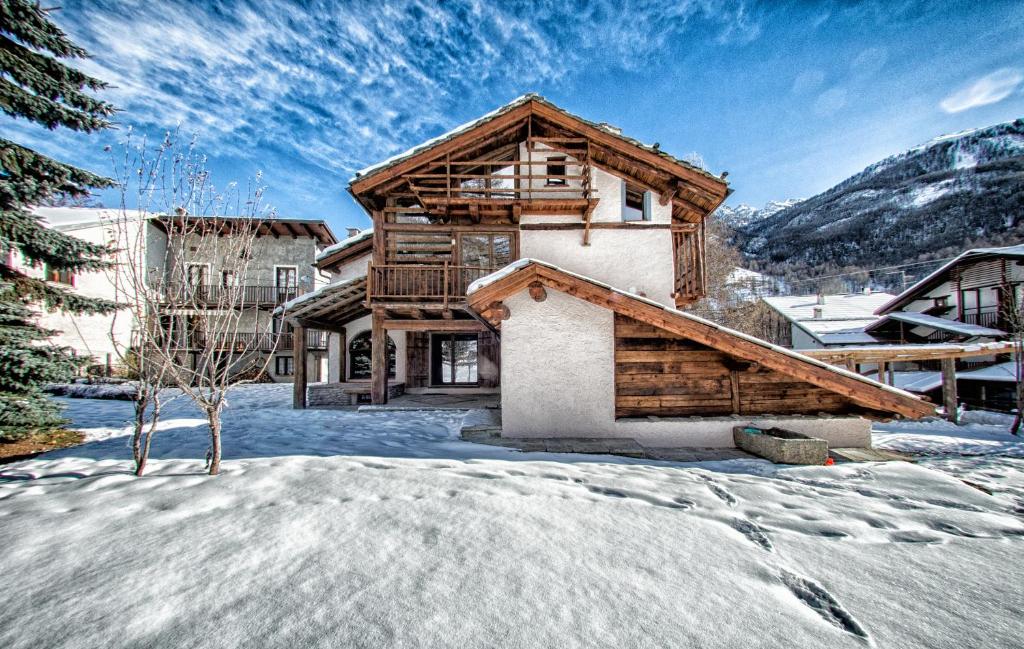 una casa de madera en invierno con nieve en Agriturismo Rivet d'Or, en Pragelato