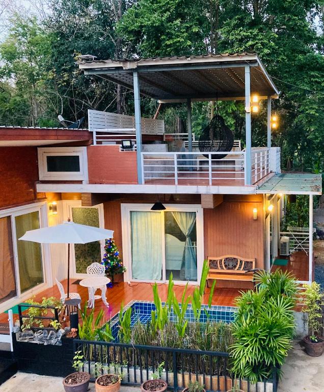 a house with a balcony with a table and an umbrella at lemoon house khaoyai in Nong Nam Daeng