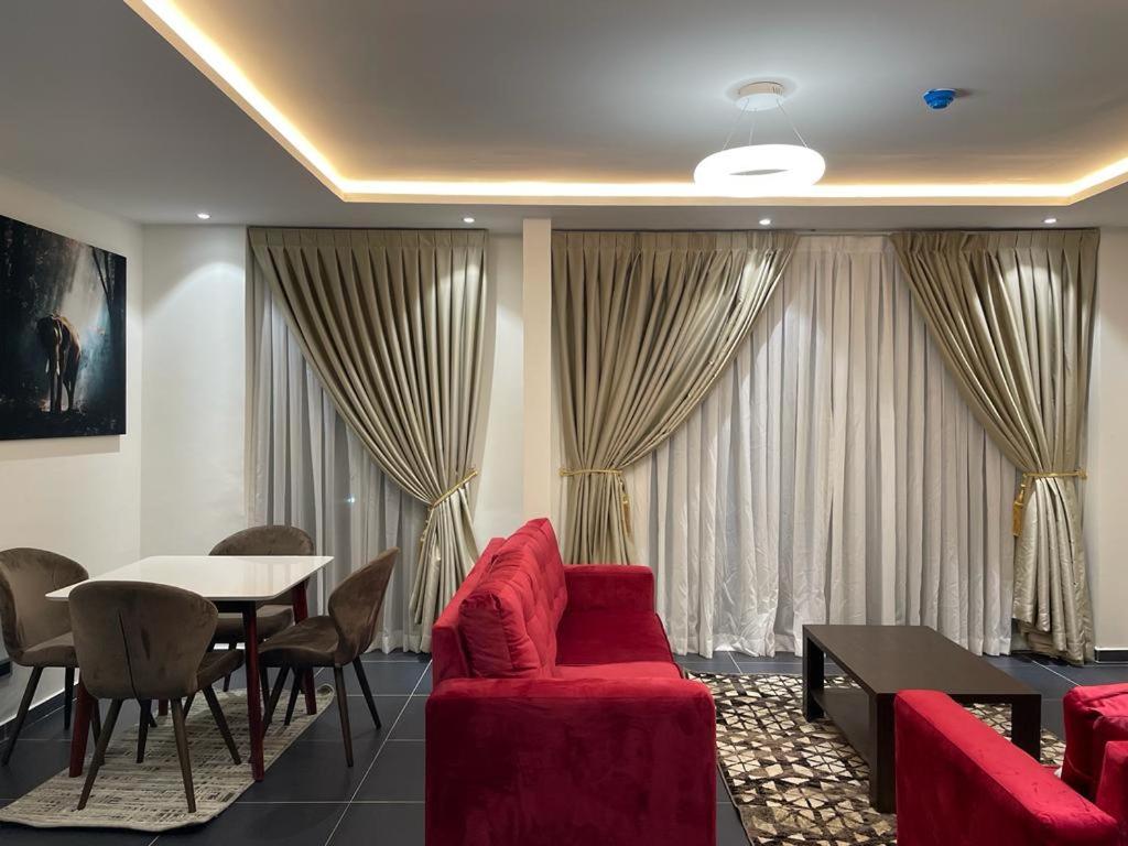 sala de estar con sofá rojo y mesa en Park D-plus Apartments Cantonments, en Accra