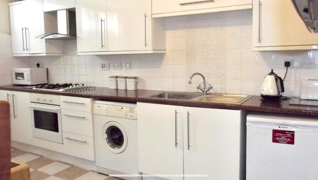 uma cozinha com armários brancos e um lavatório em Nice Double Room London Rental em Londres