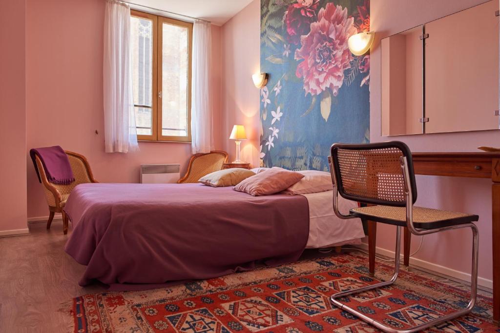a bedroom with a bed and chairs in a room at Chambre d'Elvire in Albi