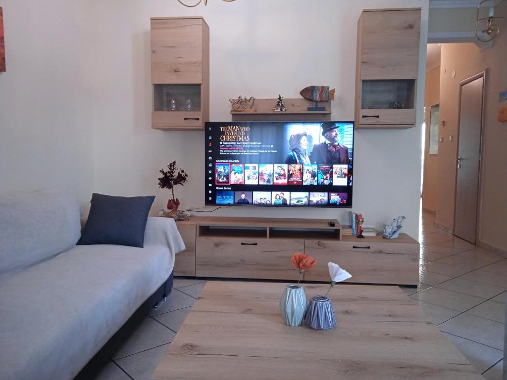uma sala de estar com um sofá e uma televisão de ecrã plano em Central Home Kavala "private parking" em Kavala