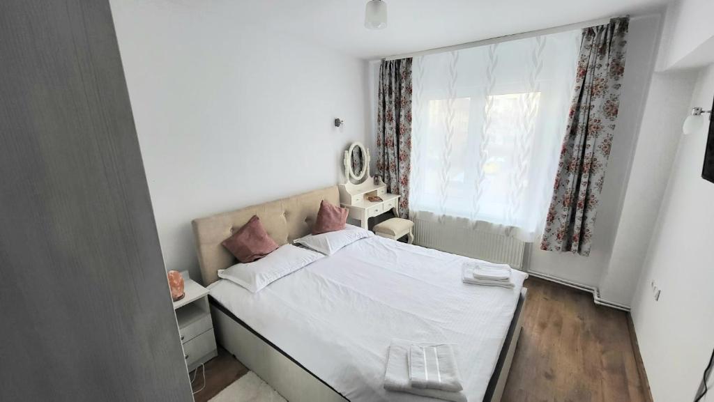 1 dormitorio con cama blanca y ventana en Apartament Ana, en Topliţa