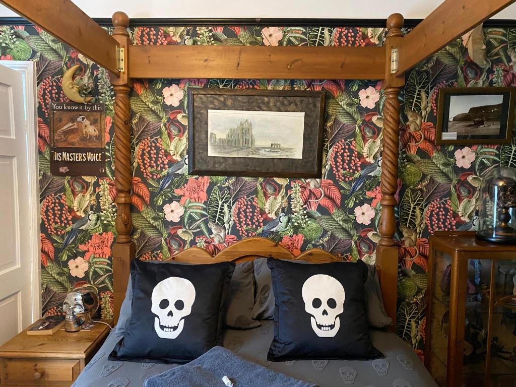 een slaapkamer met een hemelbed met schedels en bloemen bij Dracula Rooms in Whitby