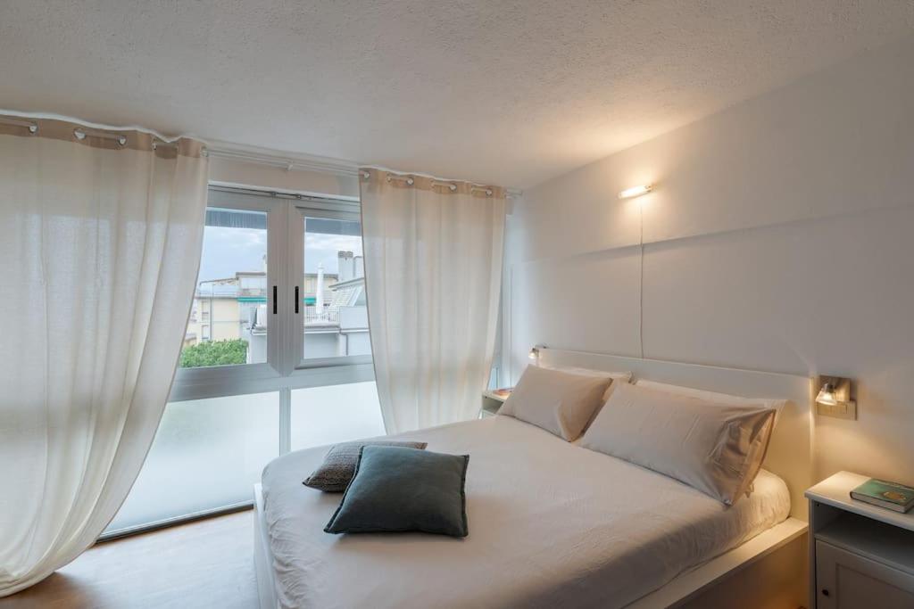 a bedroom with a white bed with a large window at [Duca d'Aosta - il soffio del mare] in Viareggio