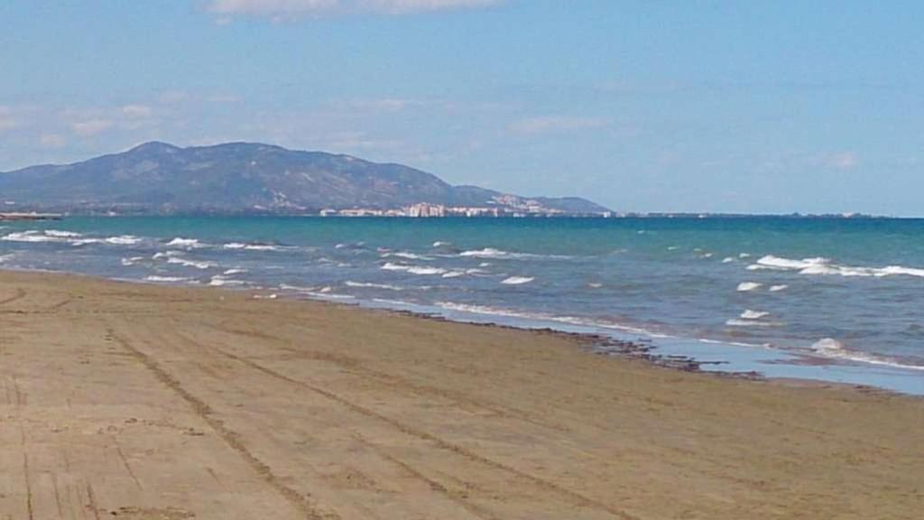 einen Strand mit dem Meer und einem Berg im Hintergrund in der Unterkunft Bajo con gran terraza en Ribera de Cabanes in Cabanes