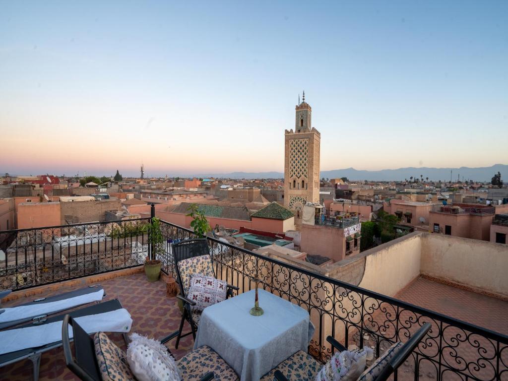 a balcony with a table and chairs and a clock tower at Dar Ben Saleh in Marrakesh
