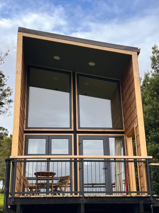 a house with windows and a balcony with a table at La isla Loft in Quellón