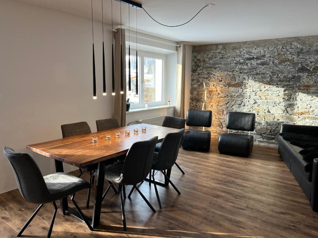 a dining room with a wooden table and black chairs at Schöne, sonnige Parterrewohung 3 Zi. mit Garten in Poschiavo