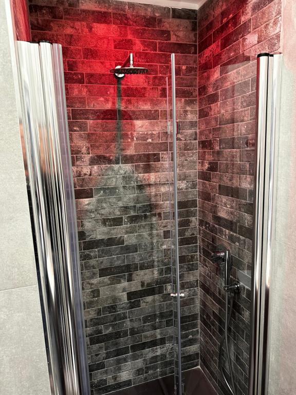 baño con ducha de cristal con pared de ladrillo en ONE HUNDRED ROOMS GARDEN en Roma