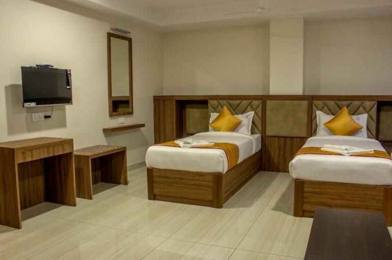 a hotel room with two beds and a television at RR Mount Elite Suites in Chennai