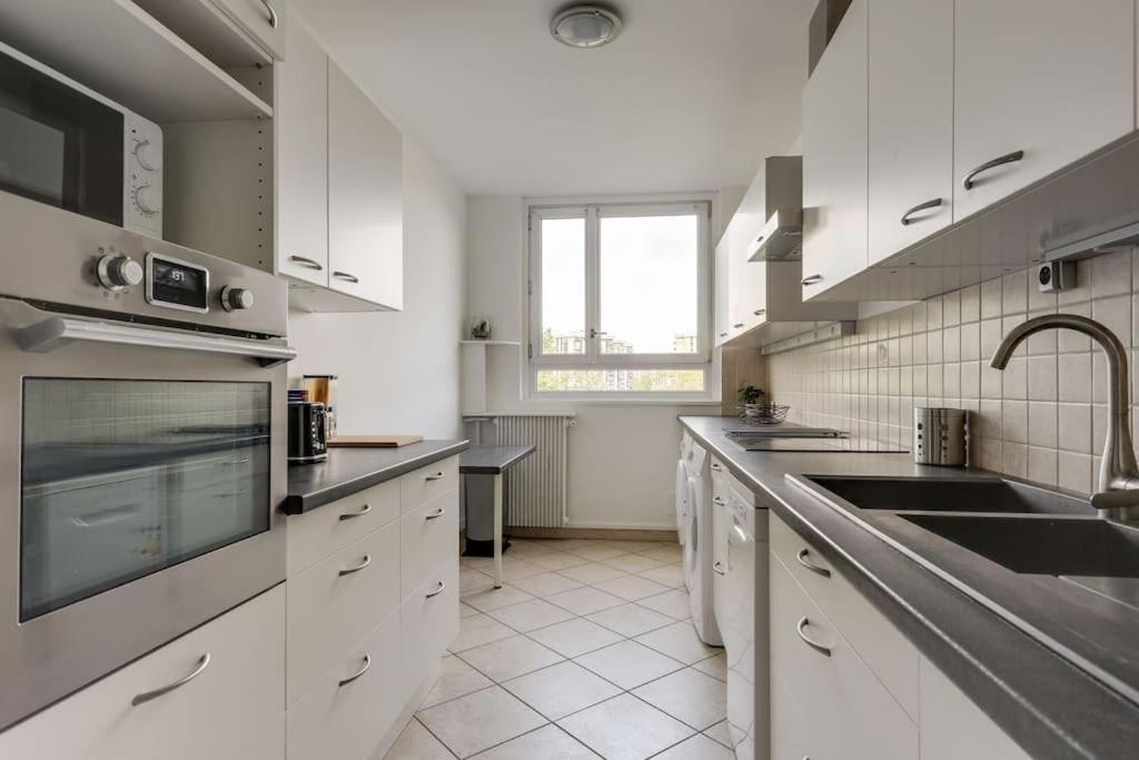 a large kitchen with white cabinets and a sink at 3 Ch 7 Personnes Calme Proche Paris in Ris-Orangis