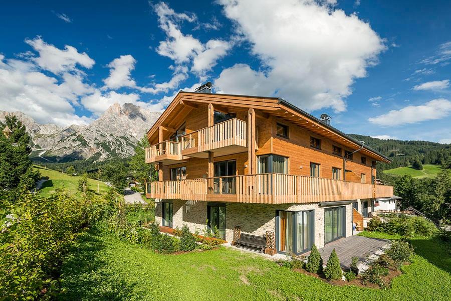 a large wooden house on a hill with mountains at Mountain-Apart Simonhof in Maria Alm am Steinernen Meer