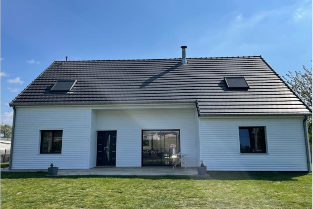 een wit huis met een zwart dak en ramen bij Villa des églantiers baie de somme in Cayeux-sur-Mer