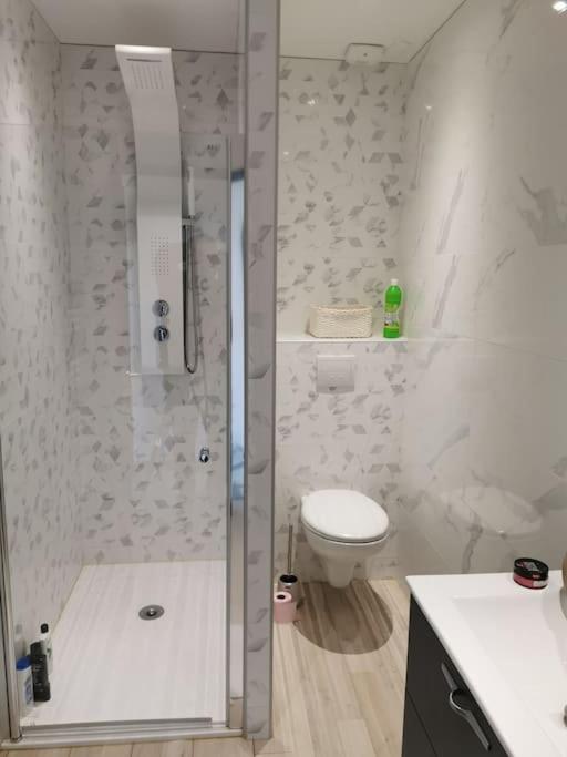 a white bathroom with a shower and a toilet at Villa des églantiers baie de somme in Cayeux-sur-Mer