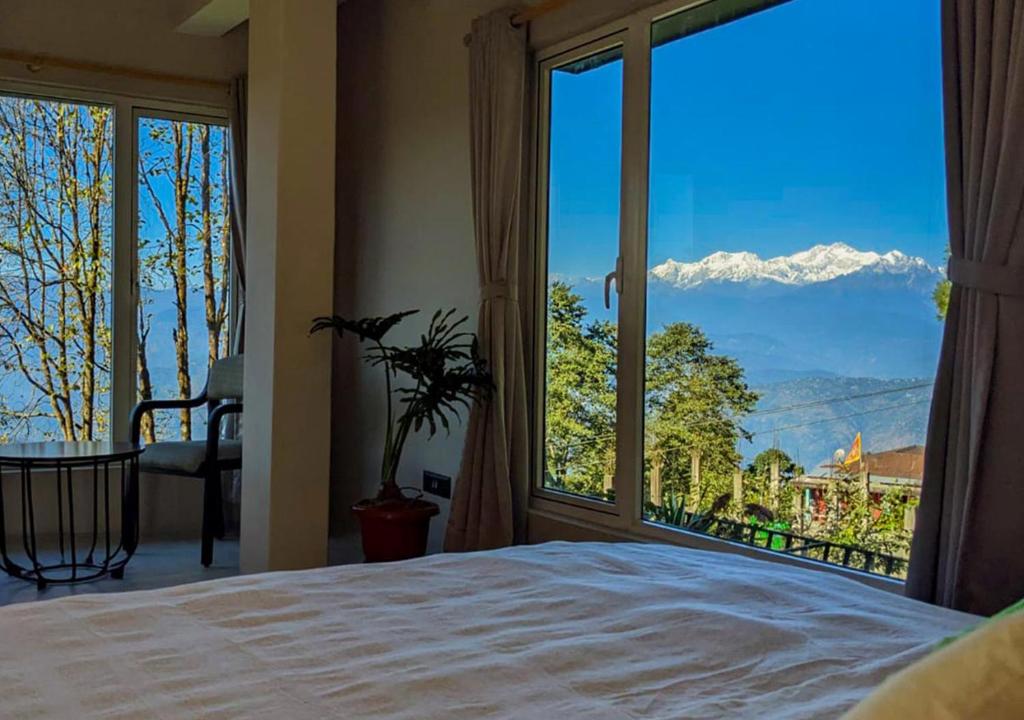 a bedroom with a large window with a mountain view at The Oak Retreat Lamahatta in Darjeeling