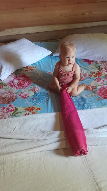 a baby sitting on a bed with a pink pillow at seven peacock Home Residence in Tangalle