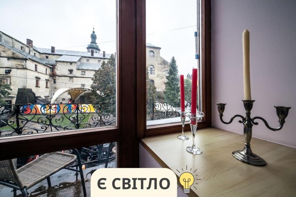 a window with two red candles and a view of a city at ROMANTIC Apartments - оn Valova street in Lviv
