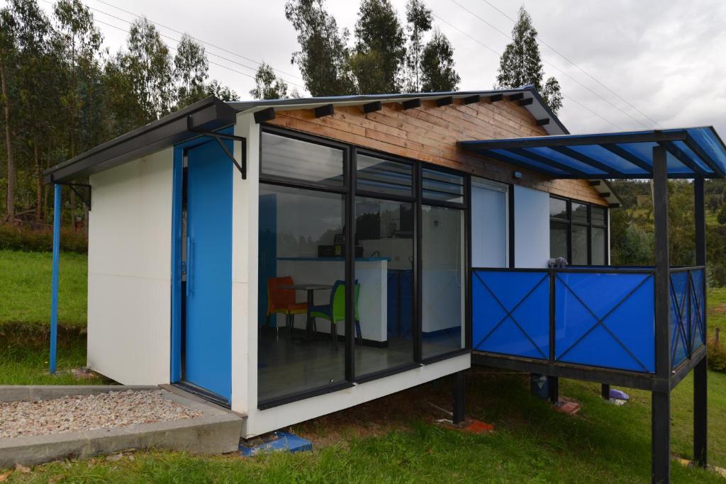 uma pequena casa com portas e janelas azuis em CABAÑAS SALEKA Paipa 