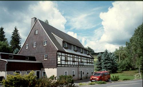 een groot gebouw met een rode bestelwagen voor de deur bij Gaststätte & Pension Alte Mühle in Dorfchemnitz