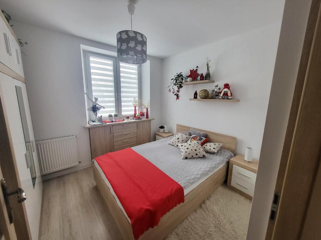 a bedroom with a bed with a red blanket and a window at Apartament Twoja Chwila in Stronie Śląskie