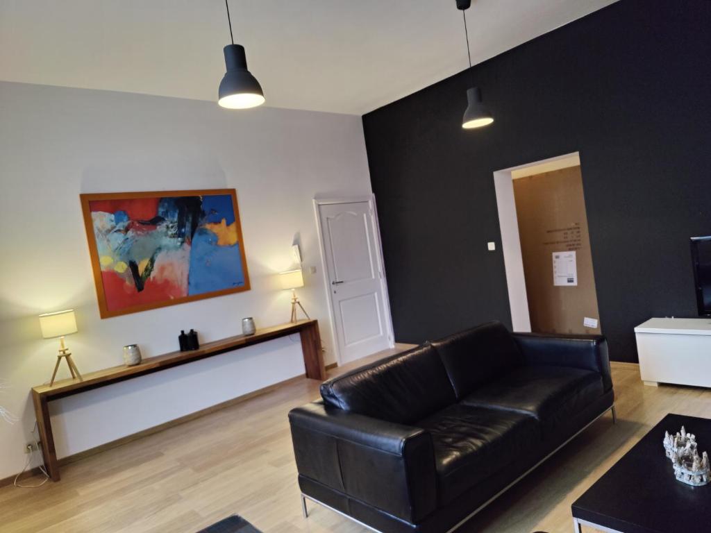 a living room with a black leather couch at B&B Leopold & Vakantiewongingen in Sint-Truiden