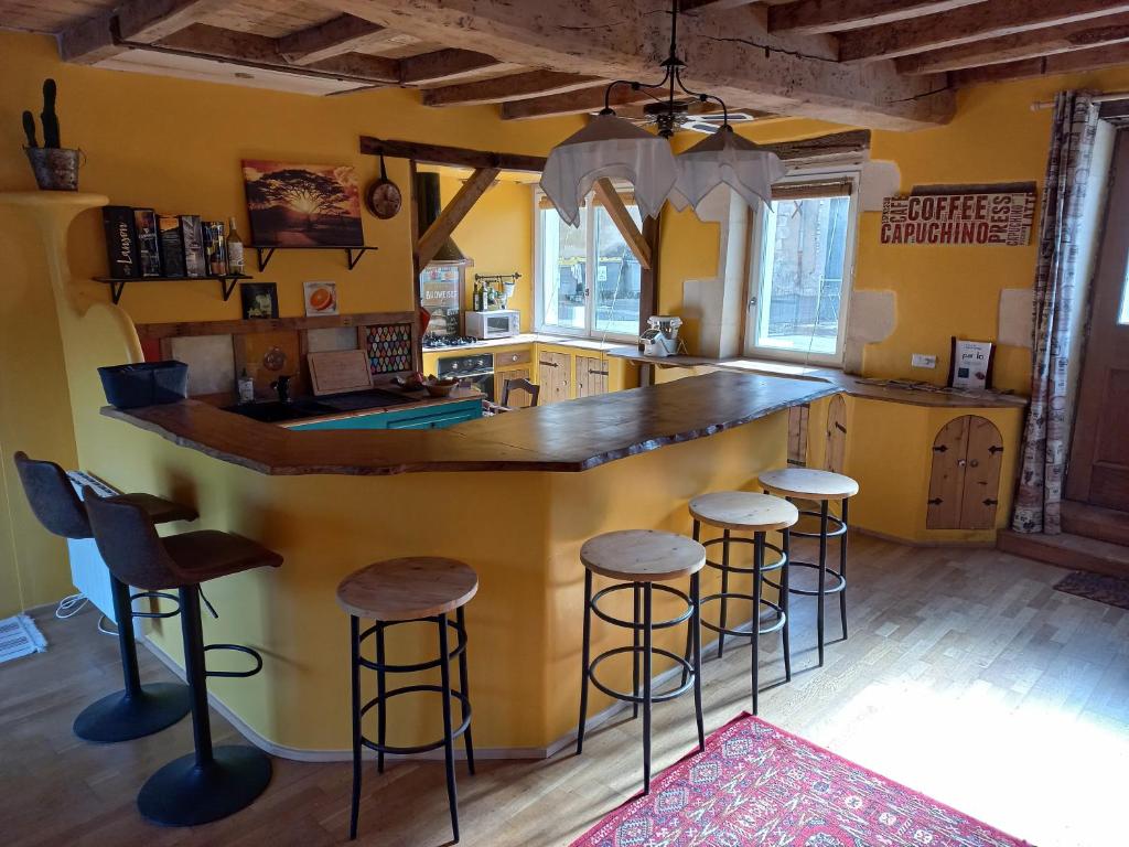 eine Küche mit einer großen Theke mit Hockern in der Unterkunft Le Moulin d'Errol in Saint-Jean-dʼAngély
