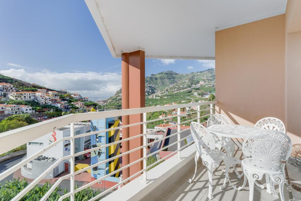 a balcony with white chairs and a view at Camara de Lobos Duplex Apartment by Holiday Rental Madeira in Câmara de Lobos