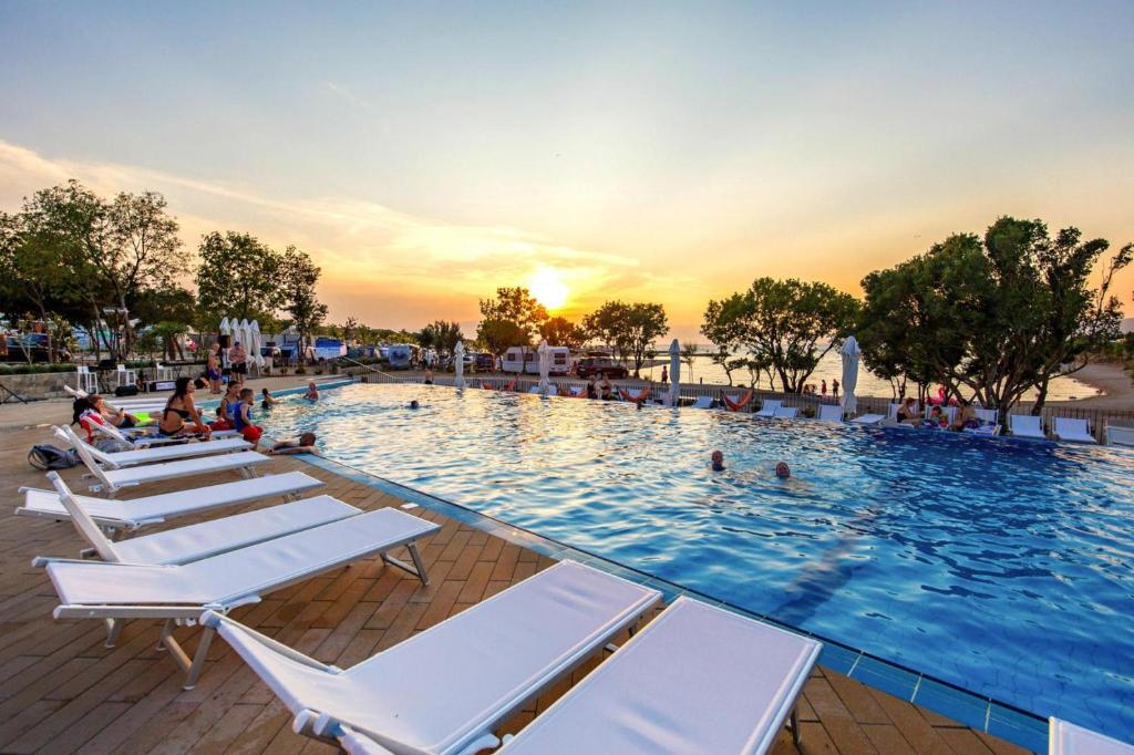 a large swimming pool with lounge chairs and people in it at Mobile Homes in Camping Omisalj, island Krk, with swimmingpool in Omišalj