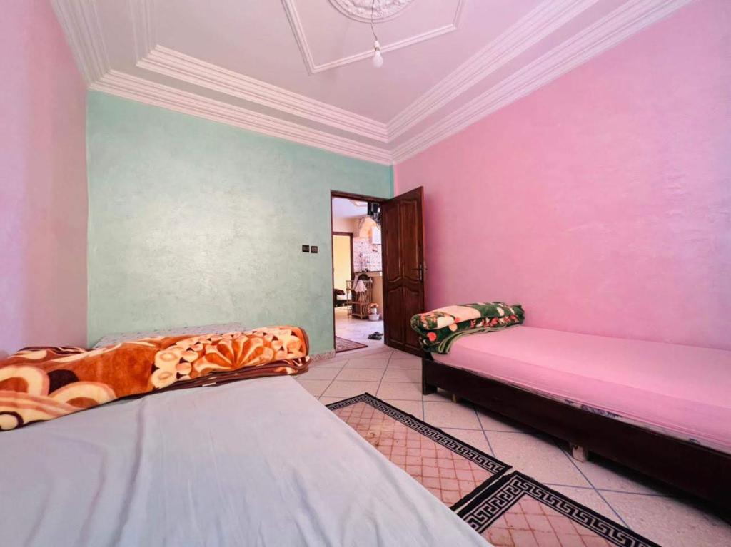Habitación con 2 camas y pared de color rosa. en Atlantic house, en Tamraght Ouzdar