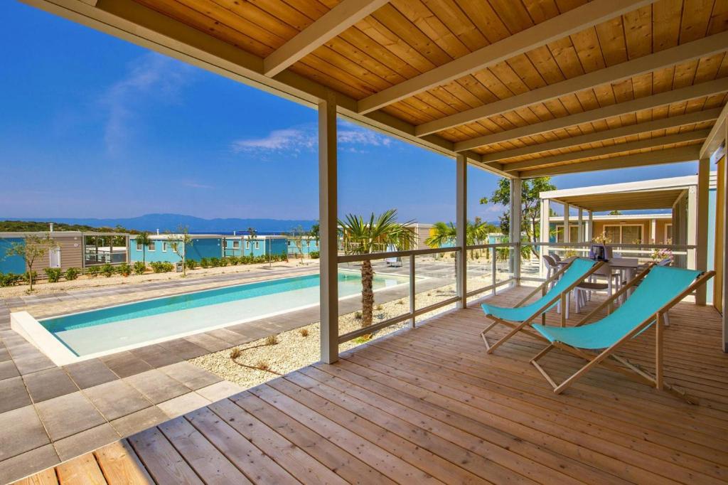 an outdoor deck with a pool and a blue chair at Mobile Homes in Camping Omisalj, island Krk, with swimmingpool in Omišalj