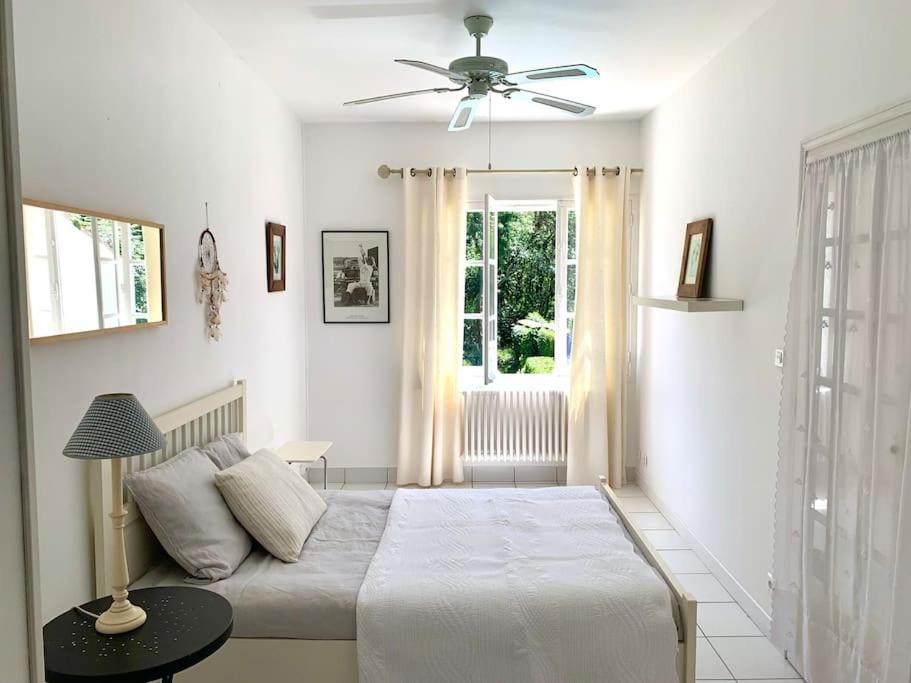 a white bedroom with a bed and a window at Maison de ville confortable avec piscine in Pons