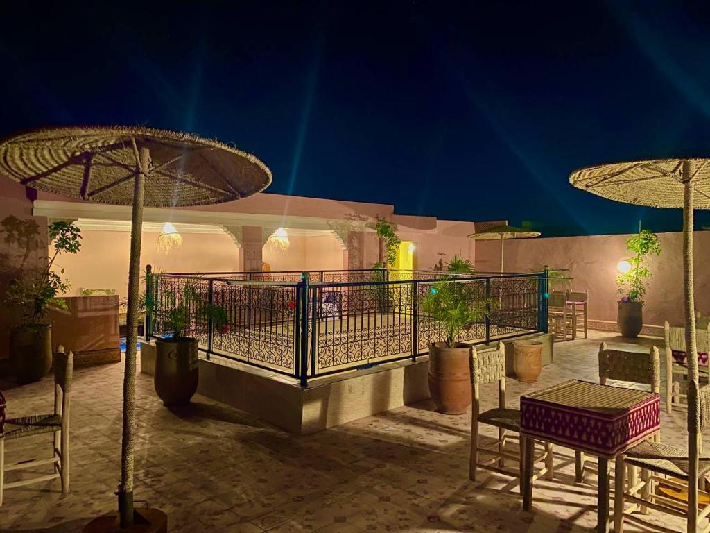 a patio with chairs and tables and umbrellas at night at Hostel World Rooftop Marrakech in Marrakesh