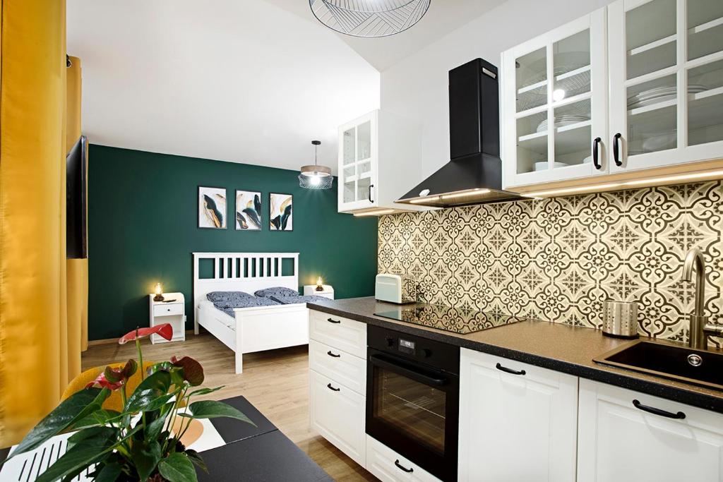 a kitchen with white cabinets and a bed in a room at Na zielonym Widoku in Wrocław