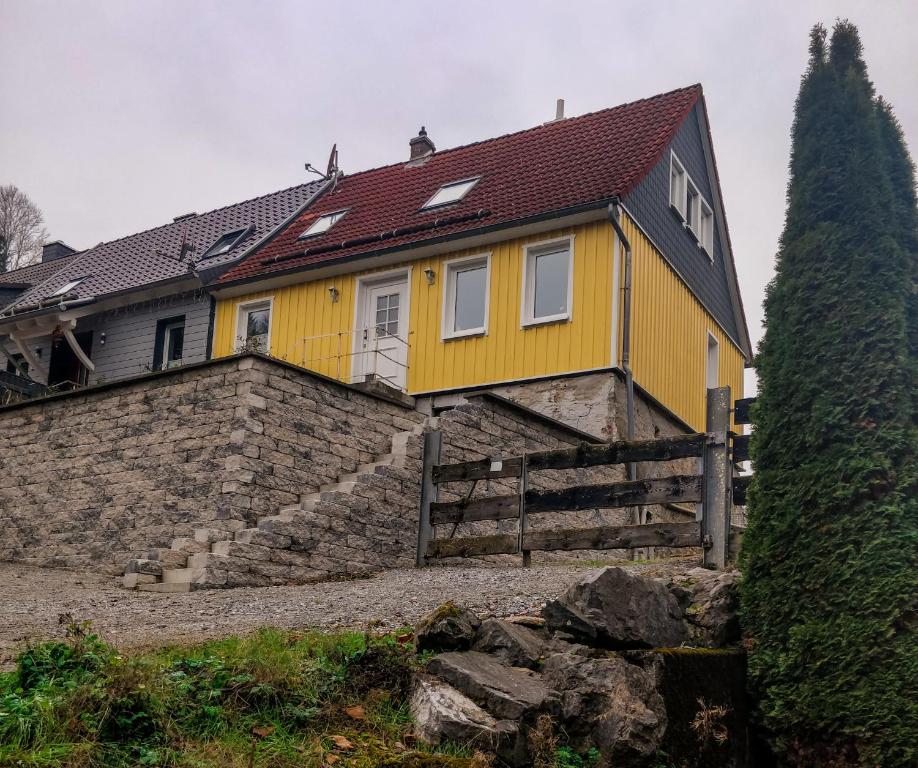 una casa gialla con un muro di pietra di Ferienhaus Felseneck Harz a Neuwerk