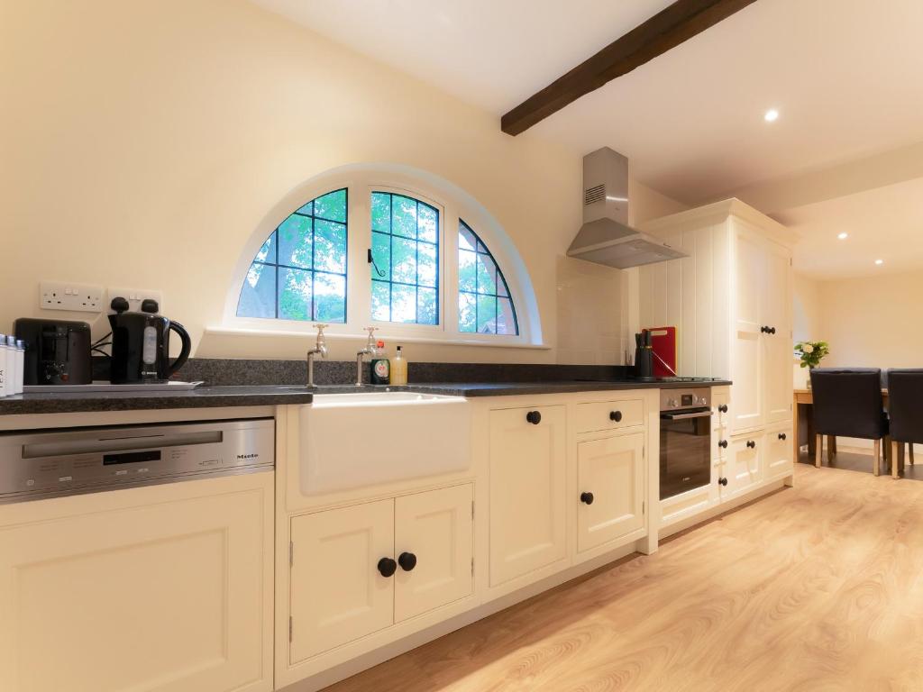 a kitchen with white cabinets and a sink and a window at The Turret in Wisley