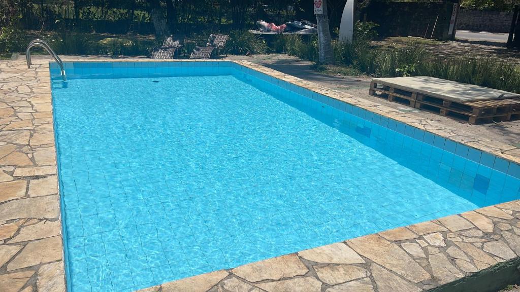 a blue swimming pool with a bench in a yard at Pousada Lifestyle Ilhabela in Ilhabela
