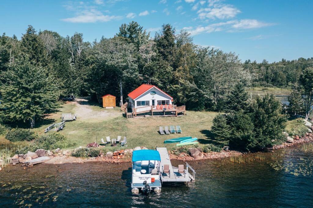 an island with a house and a boat in the water at Lakefront Stunning Home, only 30 min to Sugarloaf! in New Portland