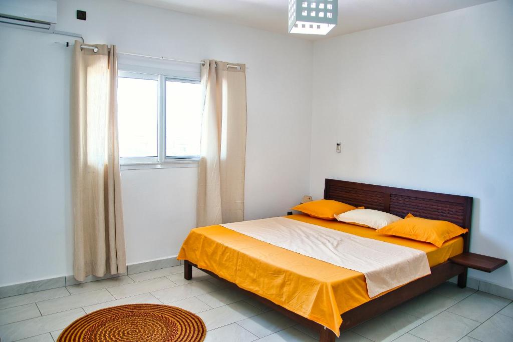 a bedroom with a bed with orange sheets and a window at RESIDENCE SAPHIR in Mahajanga