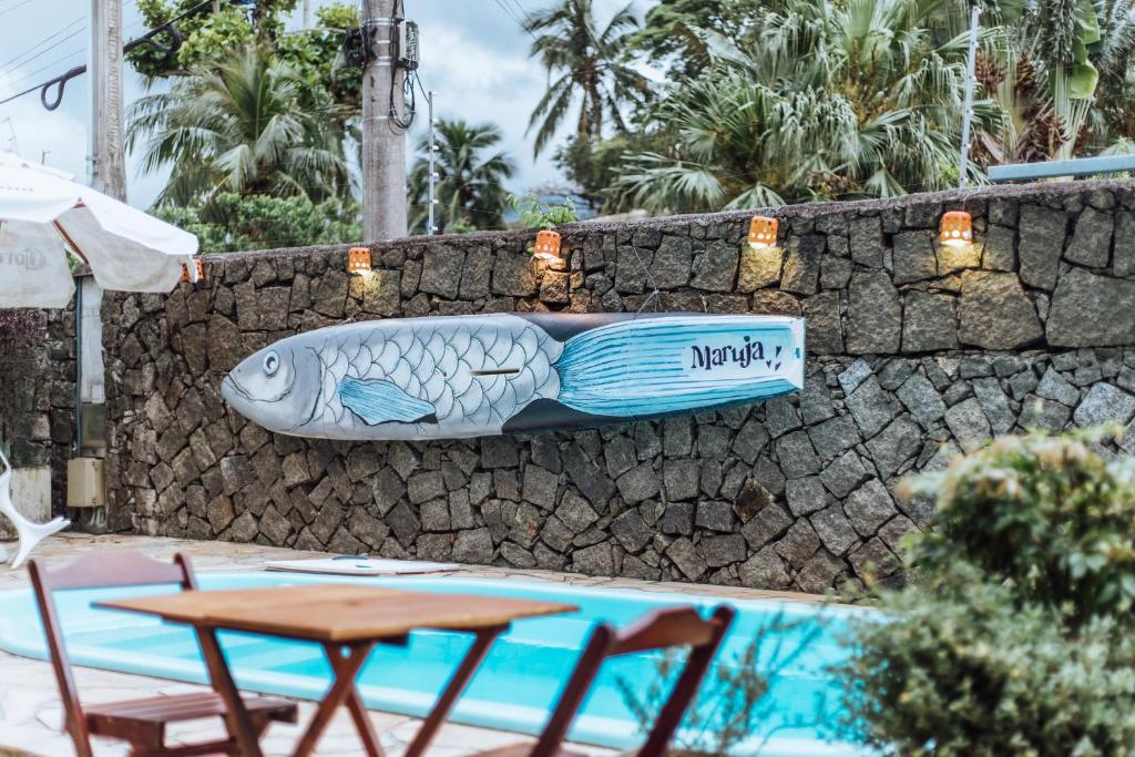 a fish sign on a stone wall next to a table at Maruja in Ilhabela