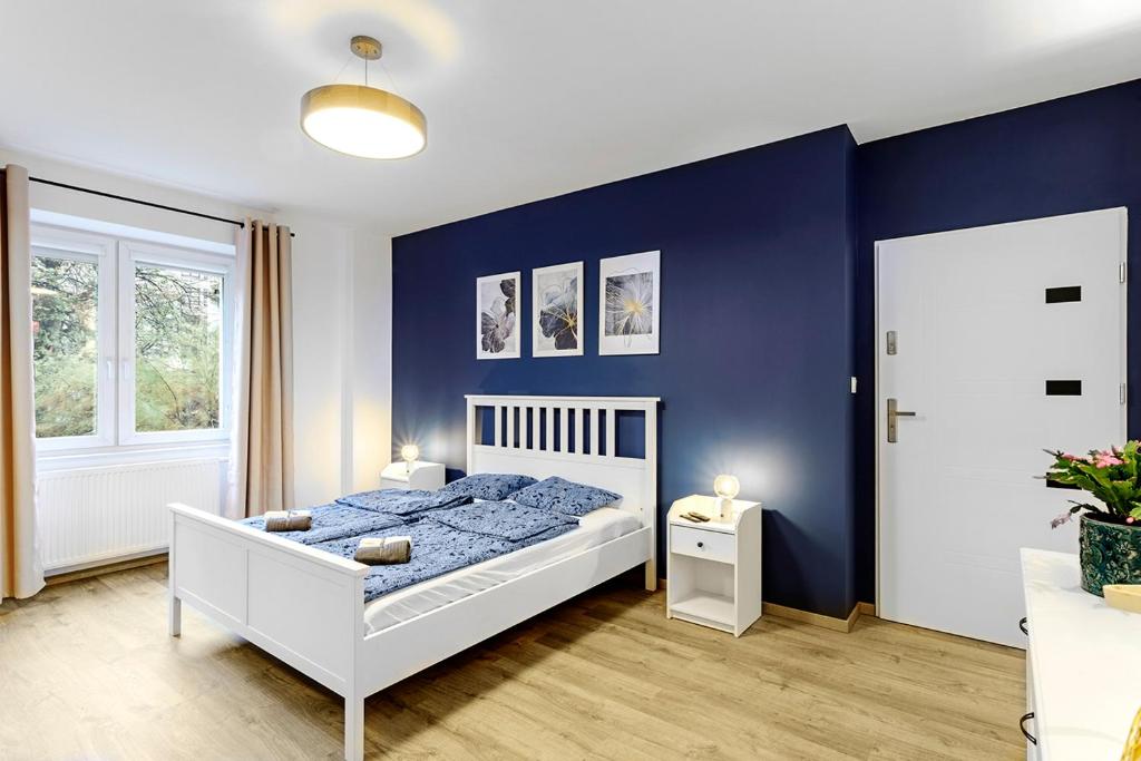 um quarto com uma cama branca e paredes azuis em Na niebieskim Widoku em Breslávia