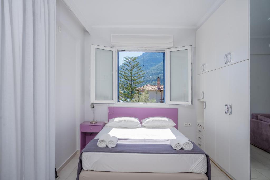 una piccola camera con un letto e due finestre di Lefkothea Apartments a Nikiana