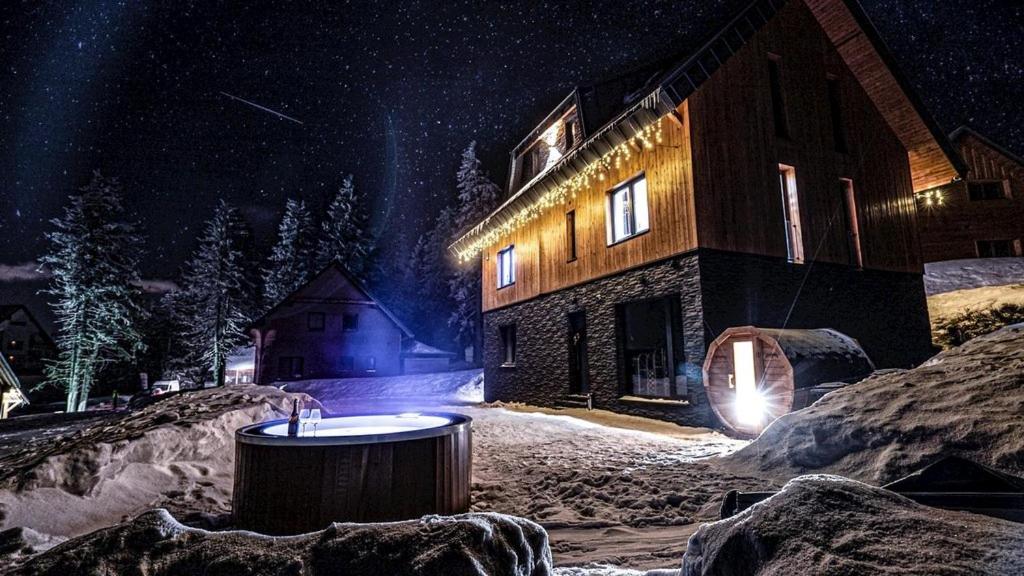 a building with a tub in the snow at night at Chata MartinSki Martinske hole in Martinske Hole